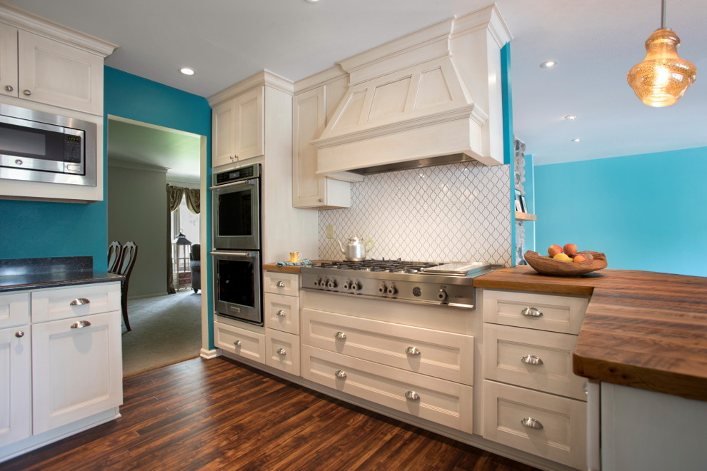 Exempel på ett mellanstort maritimt kök, med en rustik diskho, luckor med infälld panel, vita skåp, träbänkskiva, vitt stänkskydd, stänkskydd i keramik, rostfria vitvaror, vinylgolv, en halv köksö och brunt golv