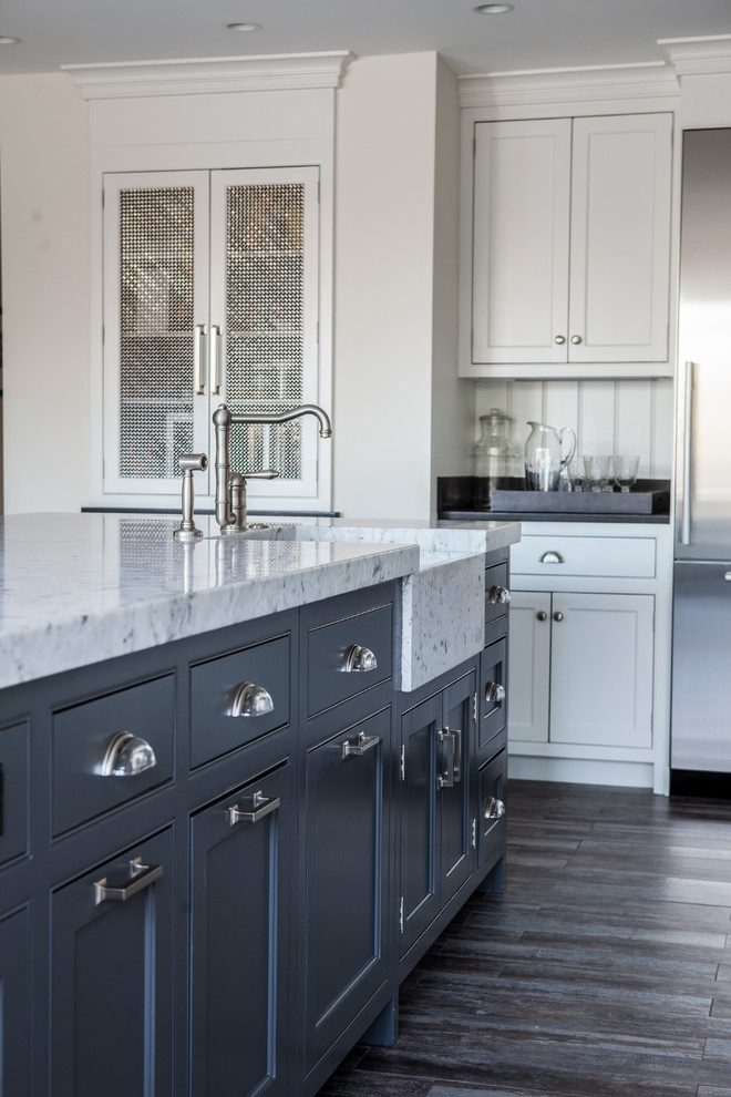 Diseño de cocina de estilo de casa de campo con fregadero sobremueble, armarios con rebordes decorativos, puertas de armario grises, encimera de mármol, salpicadero blanco, electrodomésticos de acero inoxidable, suelo de baldosas de porcelana y una isla