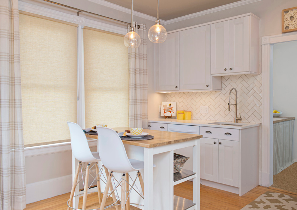 Kitchen - small transitional l-shaped light wood floor kitchen idea in Boston with shaker cabinets, white cabinets, quartz countertops, white backsplash, an island, an undermount sink, subway tile backsplash and white appliances