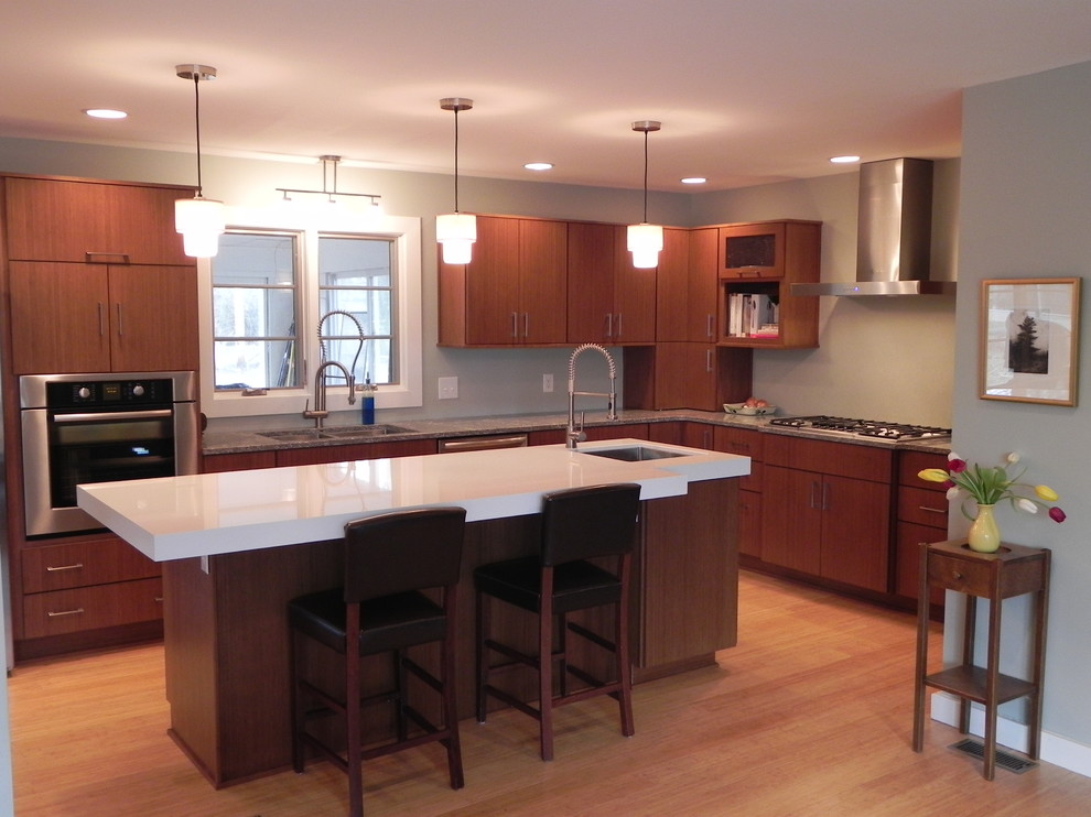 Cette photo montre une grande cuisine ouverte tendance en L et bois brun avec un placard à porte plane, un évier 2 bacs, un plan de travail en quartz, un électroménager en acier inoxydable, parquet clair, îlot et un sol beige.