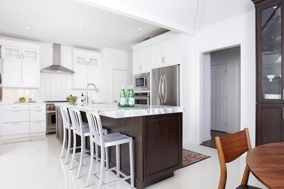 Cette photo montre une cuisine tendance avec un placard avec porte à panneau encastré, un plan de travail en quartz, une crédence blanche et îlot.