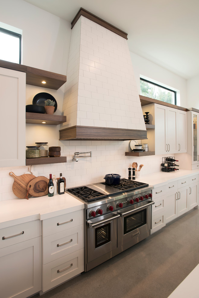 Medium sized industrial l-shaped open plan kitchen in Miami with a double-bowl sink, shaker cabinets, beige cabinets, engineered stone countertops, beige splashback, ceramic splashback, stainless steel appliances, concrete flooring and an island.