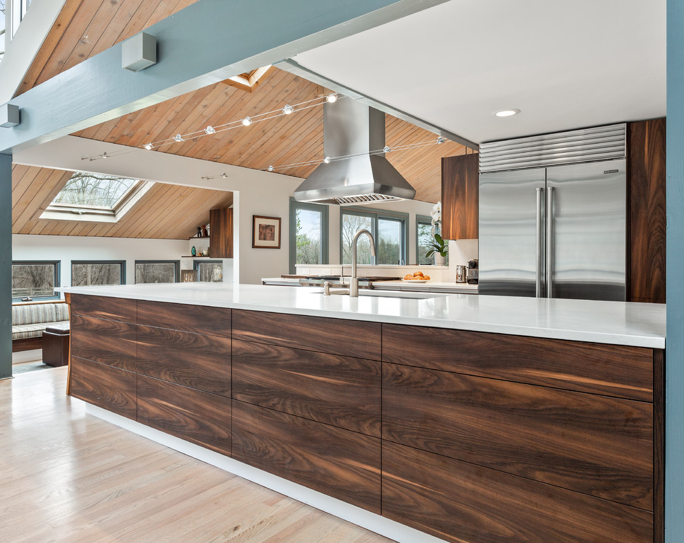 Inspiration for a large midcentury kitchen/diner in Chicago with a submerged sink, flat-panel cabinets, brown cabinets, quartz worktops, stainless steel appliances, light hardwood flooring, an island, yellow floors and white worktops.