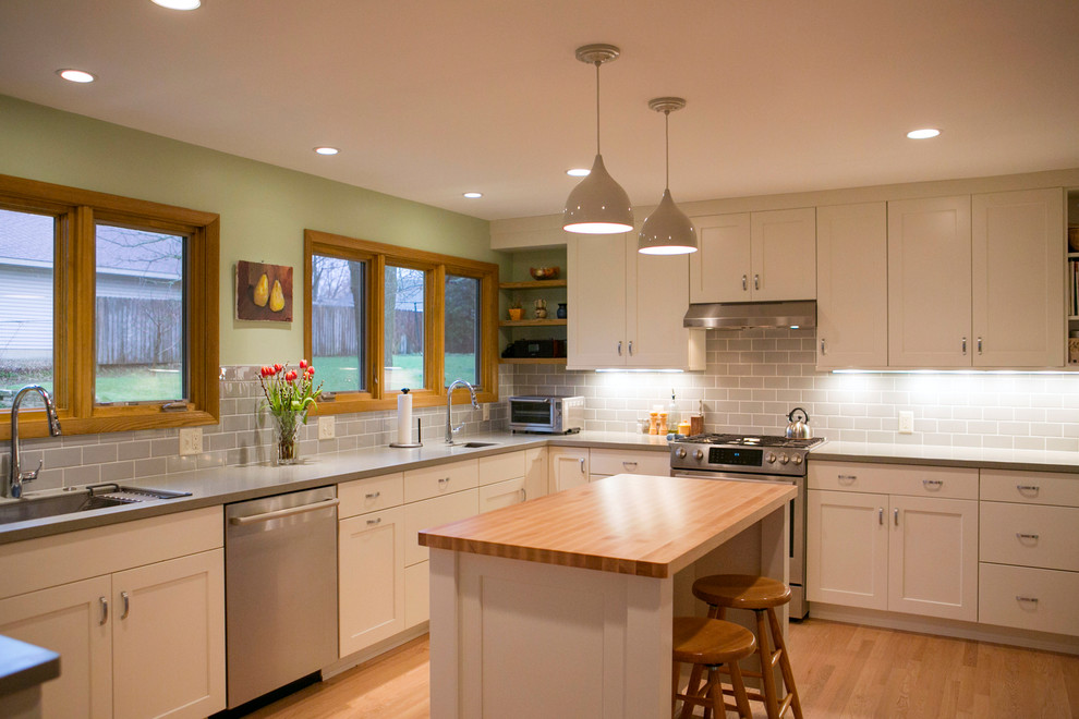 Foto di una cucina minimalista con ante in stile shaker, ante bianche, top in cemento e parquet chiaro