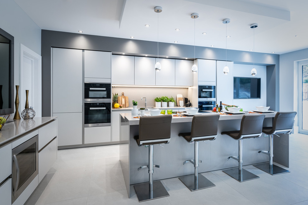Design ideas for a large contemporary single-wall kitchen/diner in Hampshire with flat-panel cabinets, grey cabinets, engineered stone countertops, grey splashback, stone slab splashback, stainless steel appliances, an island, grey worktops and grey floors.