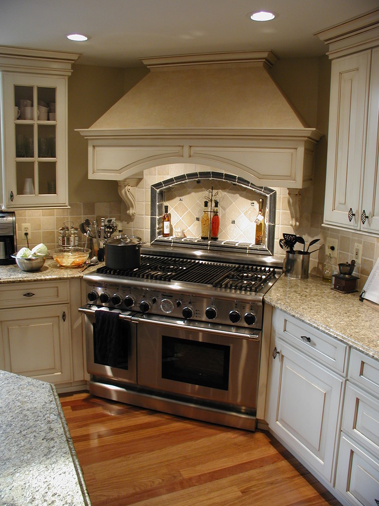 Photo of a classic l-shaped kitchen/diner in Detroit with a double-bowl sink, raised-panel cabinets, white cabinets and stainless steel appliances.