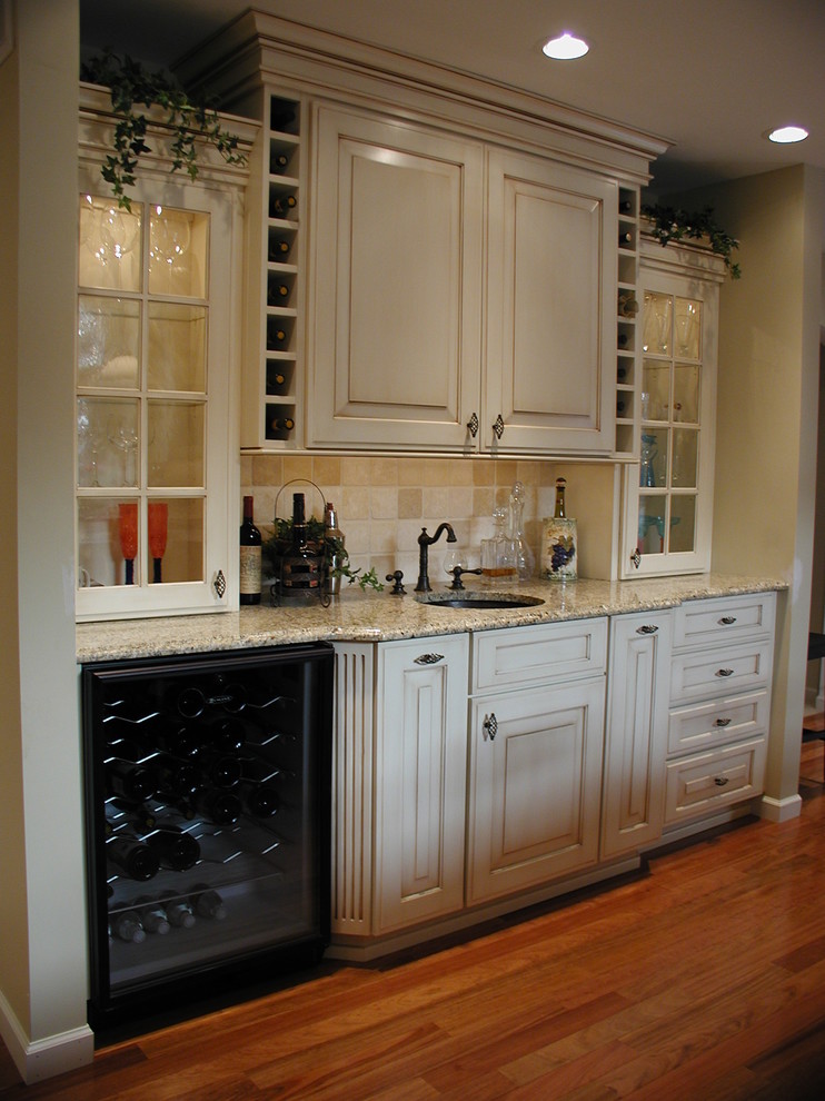 Klassisk inredning av ett u-kök, med en enkel diskho, luckor med upphöjd panel, vita skåp, granitbänkskiva och svarta vitvaror