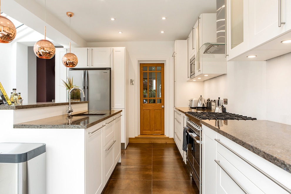 Example of a mid-sized trendy l-shaped open concept kitchen design in London with an undermount sink, shaker cabinets, white cabinets, granite countertops and an island