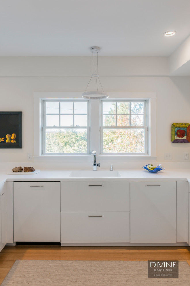 Modern inredning av ett mellanstort kök, med en undermonterad diskho, släta luckor, vita skåp, bänkskiva i koppar, vitt stänkskydd, stänkskydd i porslinskakel, rostfria vitvaror, ljust trägolv, en halv köksö och beiget golv