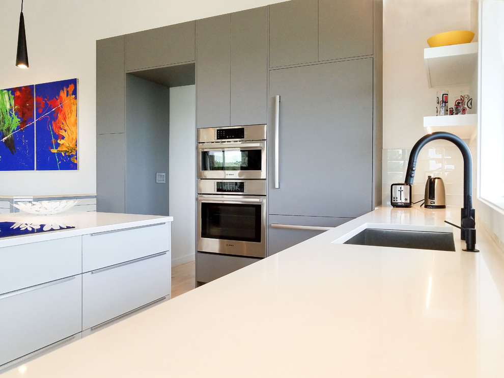 Exempel på ett mellanstort modernt vit linjärt vitt kök med öppen planlösning, med en undermonterad diskho, släta luckor, grå skåp, bänkskiva i kvarts, grått stänkskydd, stänkskydd i glaskakel, färgglada vitvaror, ljust trägolv och en köksö