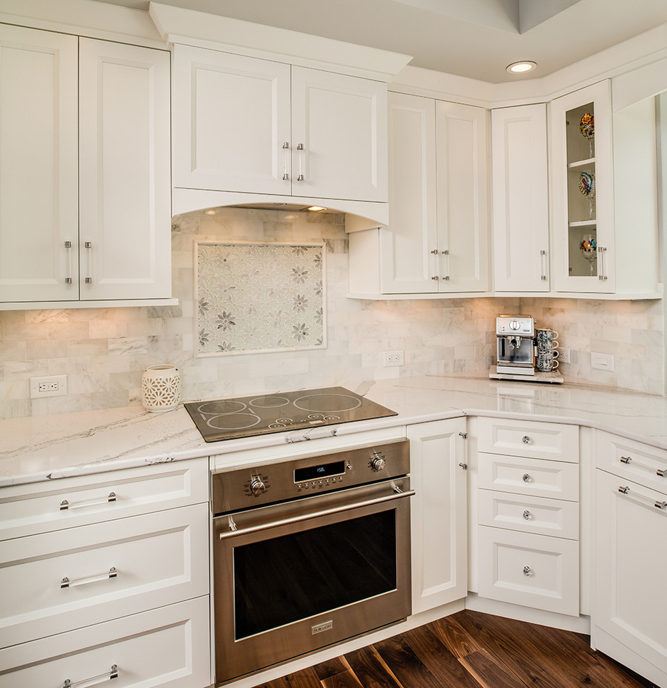 Example of a mid-sized trendy u-shaped dark wood floor eat-in kitchen design in Other with an undermount sink, recessed-panel cabinets, white cabinets, quartz countertops, gray backsplash, stone tile backsplash and stainless steel appliances