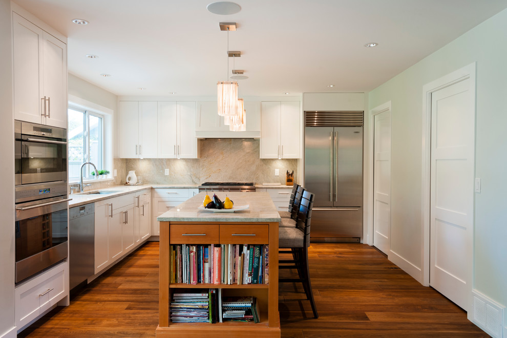 Inspiration for a large transitional l-shaped medium tone wood floor open concept kitchen remodel in Vancouver with an undermount sink, shaker cabinets, white cabinets, quartzite countertops, gray backsplash, stone slab backsplash, stainless steel appliances and an island