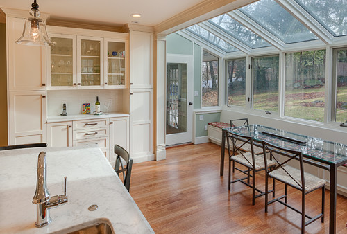 Bright kitchen with engineered wood flooring, glass backsplash cabinets, and sunroom dining area – modern Canadian home design