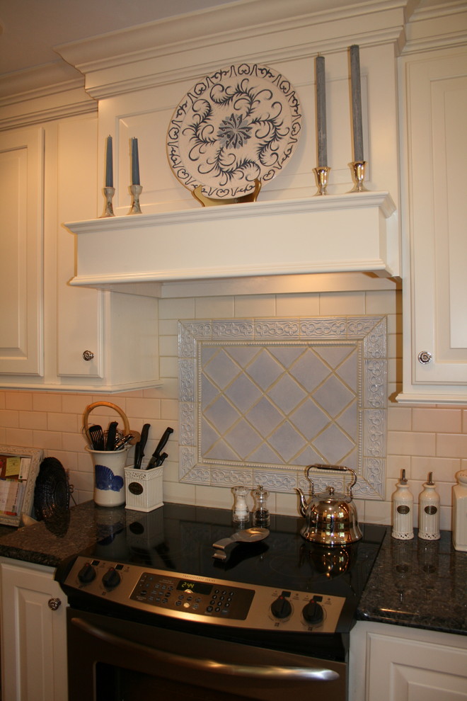 Bild på ett stort vintage kök, med en undermonterad diskho, luckor med upphöjd panel, vita skåp, granitbänkskiva, vitt stänkskydd, stänkskydd i keramik, rostfria vitvaror och mellanmörkt trägolv
