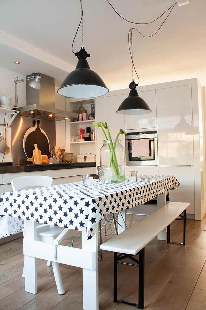 Imagen de cocina comedor ecléctica con armarios con paneles lisos, puertas de armario blancas y electrodomésticos de acero inoxidable