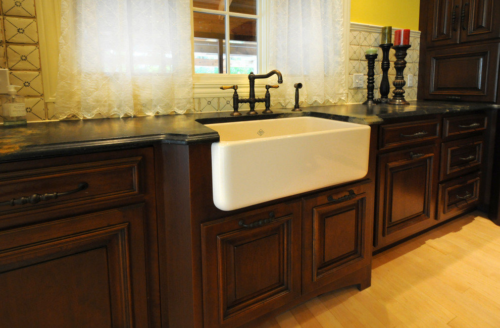 Example of a tuscan l-shaped eat-in kitchen design in Other with a farmhouse sink, beaded inset cabinets, dark wood cabinets, beige backsplash, subway tile backsplash and paneled appliances