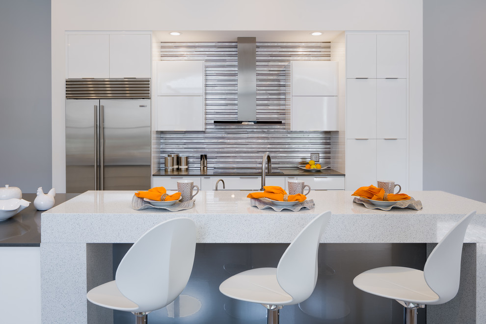 Offene, Mittelgroße Moderne Küche mit flächenbündigen Schrankfronten, weißen Schränken, Küchenrückwand in Metallic, Rückwand aus Stäbchenfliesen, Küchengeräten aus Edelstahl und Kücheninsel in Miami