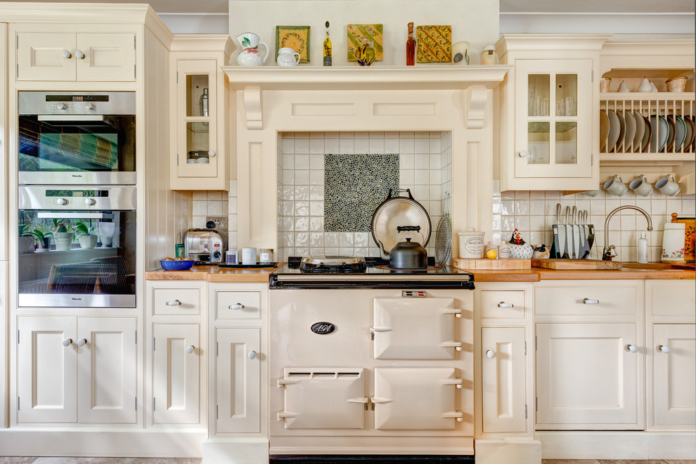 Design ideas for a farmhouse kitchen in Devon with beaded cabinets, beige cabinets, multi-coloured splashback, white appliances and wood worktops.