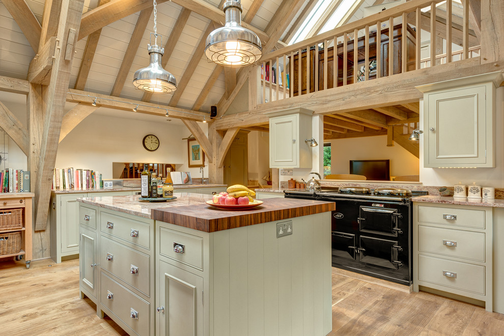 Expansive rural kitchen in Devon with beaded cabinets, beige cabinets, granite worktops, black appliances, medium hardwood flooring and an island.
