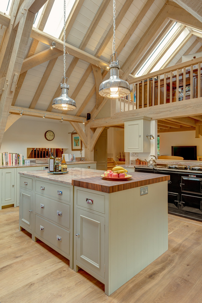 Große Landhausstil Wohnküche in U-Form mit Kassettenfronten, Granit-Arbeitsplatte, Kücheninsel und hellem Holzboden in Devon