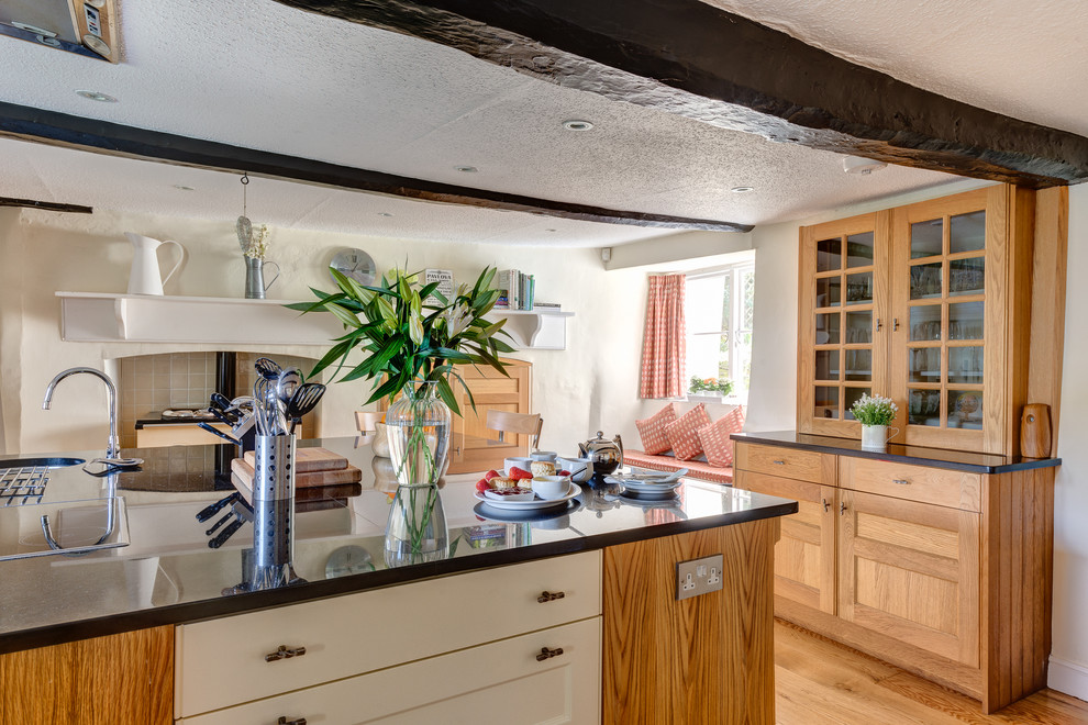 Große Landhausstil Wohnküche mit Schrankfronten mit vertiefter Füllung, hellbraunen Holzschränken, Granit-Arbeitsplatte, bunten Elektrogeräten, braunem Holzboden und Kücheninsel in Devon