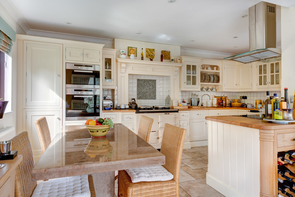 Bild på ett stort lantligt kök, med en undermonterad diskho, luckor med infälld panel, skåp i slitet trä, träbänkskiva, vitt stänkskydd, färgglada vitvaror, klinkergolv i keramik och en köksö