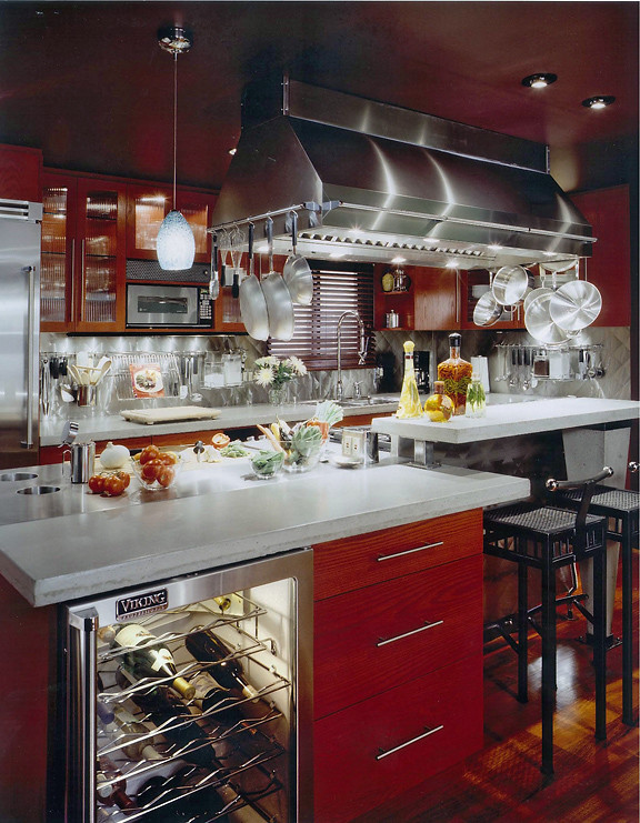 Inspiration för små eklektiska kök, med en dubbel diskho, släta luckor, röda skåp, bänkskiva i betong, stänkskydd med metallisk yta, rostfria vitvaror, mellanmörkt trägolv och en köksö