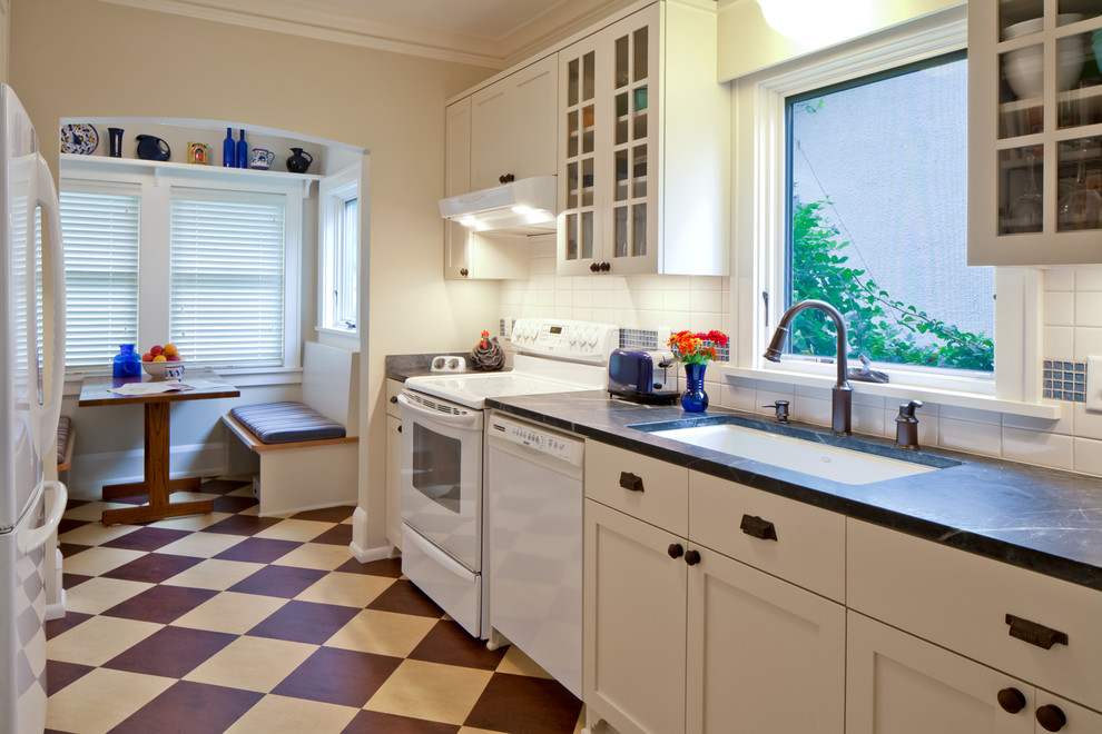 Design ideas for a medium sized traditional galley enclosed kitchen in Minneapolis with a submerged sink, recessed-panel cabinets, white cabinets, soapstone worktops, white splashback, glass tiled splashback, white appliances, lino flooring and no island.