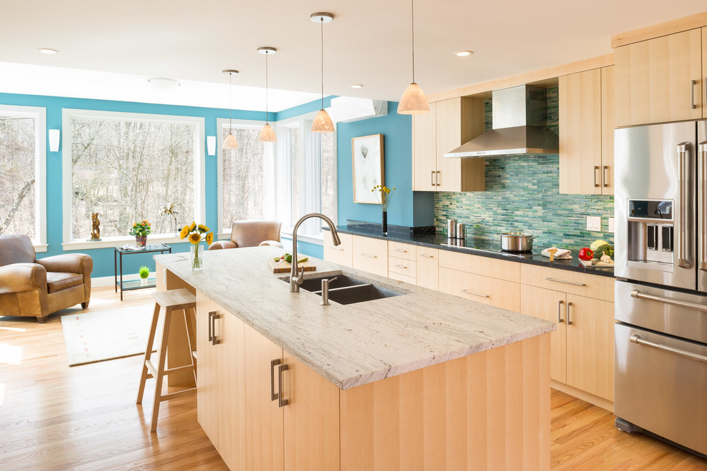 Photo of a contemporary open plan kitchen in Boston with a double-bowl sink, flat-panel cabinets, light wood cabinets, multi-coloured splashback, matchstick tiled splashback, stainless steel appliances, light hardwood flooring and an island.
