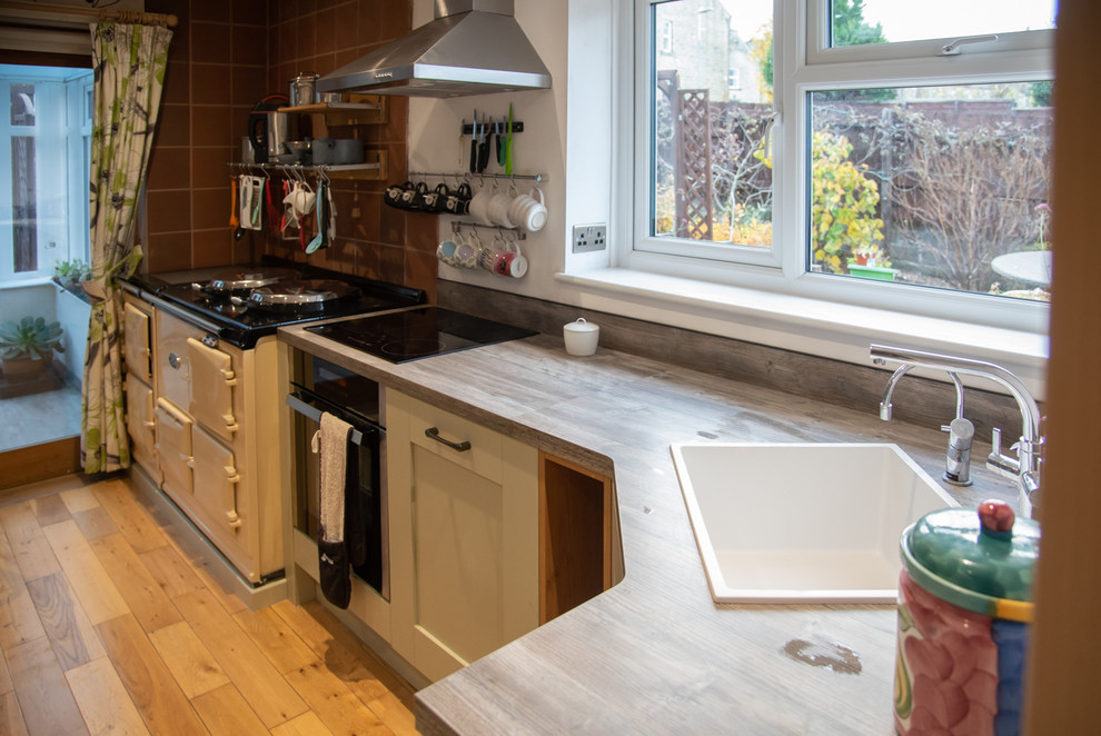 Immagine di una piccola cucina tradizionale con lavello da incasso, ante in stile shaker, ante grigie, top in laminato, pavimento in laminato, penisola e pavimento marrone