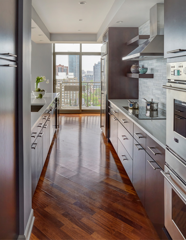Eat-in kitchen - mid-sized contemporary galley medium tone wood floor and gray floor eat-in kitchen idea in Chicago with a single-bowl sink, flat-panel cabinets, dark wood cabinets, quartz countertops, gray backsplash, marble backsplash, stainless steel appliances and a peninsula