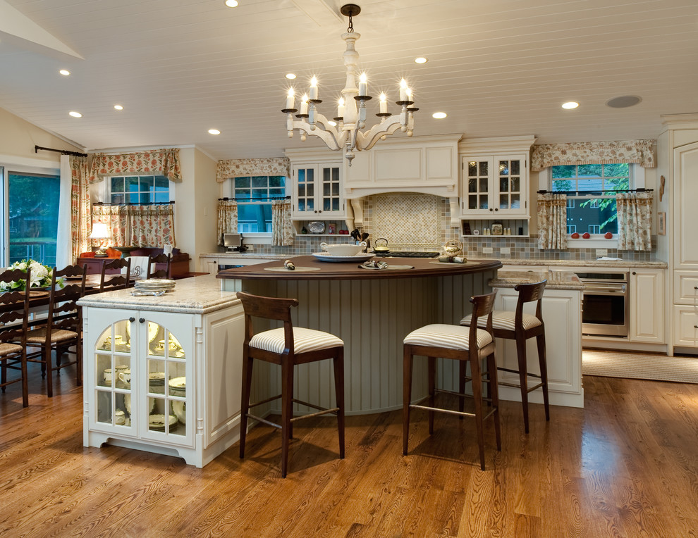Example of a large classic single-wall light wood floor eat-in kitchen design in Baltimore with a farmhouse sink, raised-panel cabinets, yellow cabinets, granite countertops, beige backsplash, stone tile backsplash and paneled appliances