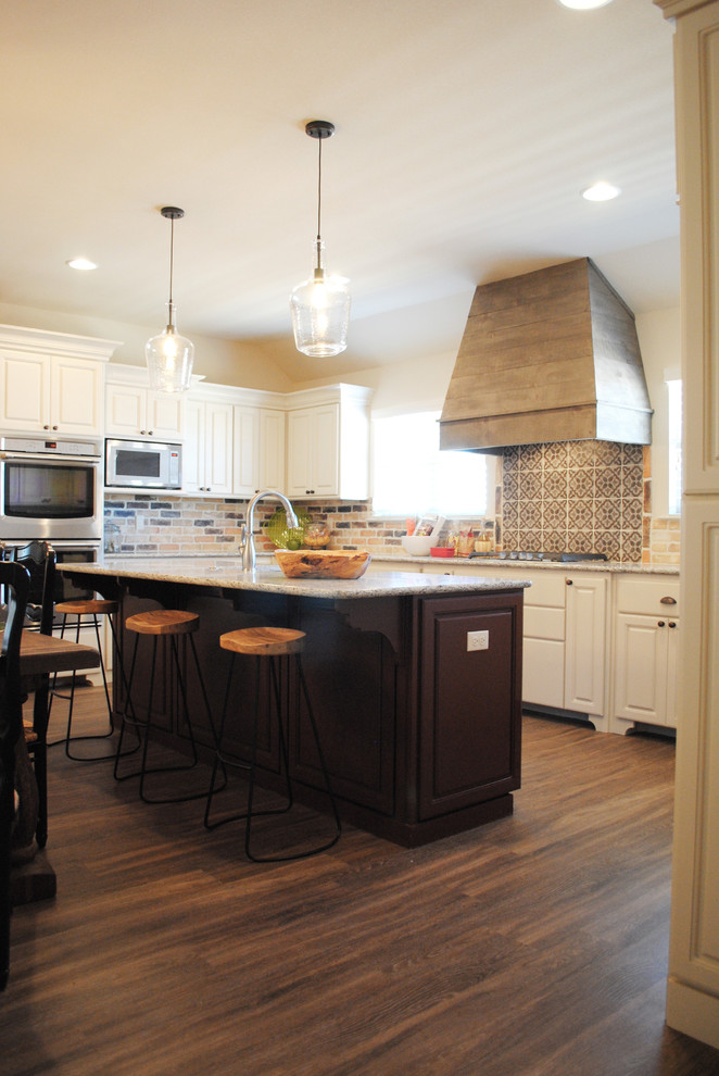 Foto på ett mellanstort eklektiskt kök, med en rustik diskho, luckor med infälld panel, vita skåp, granitbänkskiva, brunt stänkskydd, stänkskydd i cementkakel, rostfria vitvaror, vinylgolv och en köksö