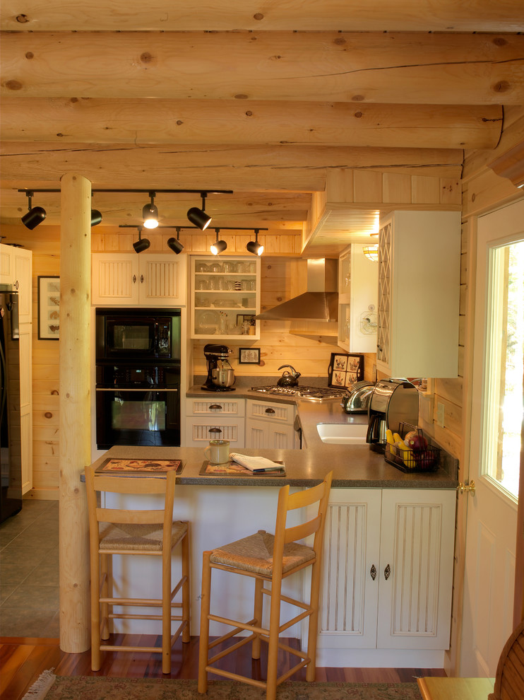 Esempio di una piccola cucina stile rurale con lavello stile country, ante bianche, top in granito, elettrodomestici neri, pavimento in gres porcellanato e ante con riquadro incassato