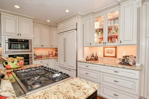 This is an example of a classic l-shaped kitchen/diner in DC Metro with raised-panel cabinets, white cabinets, granite worktops, stainless steel appliances and an island.