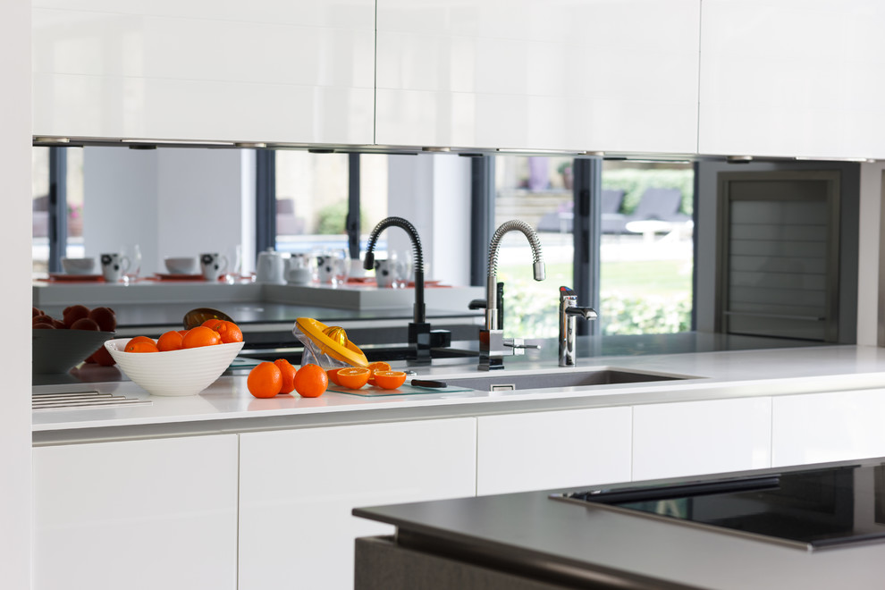 Diseño de cocina contemporánea con fregadero bajoencimera, armarios con paneles lisos, puertas de armario blancas y salpicadero con efecto espejo