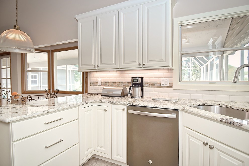 Inredning av ett klassiskt stort flerfärgad flerfärgat kök, med en dubbel diskho, luckor med upphöjd panel, vita skåp, granitbänkskiva, vitt stänkskydd, stänkskydd i tunnelbanekakel, rostfria vitvaror, vinylgolv, en halv köksö och grått golv