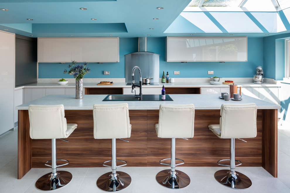 Идея дизайна: угловая кухня в современном стиле с накладной мойкой, плоскими фасадами, белыми фасадами, синим фартуком, островом, белым полом и белой столешницей