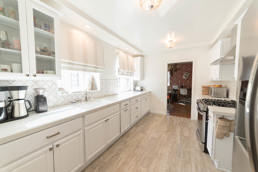 Small trendy galley light wood floor and brown floor enclosed kitchen photo in San Francisco with a drop-in sink, raised-panel cabinets, white cabinets, marble countertops, multicolored backsplash, marble backsplash, stainless steel appliances, no island and white countertops
