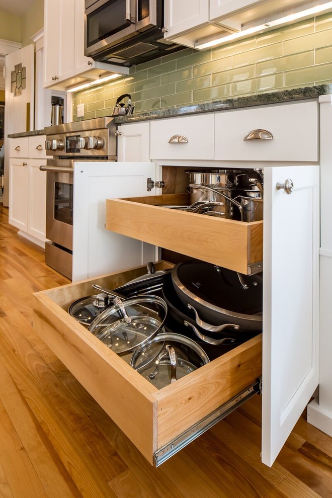 Photo of a medium sized classic galley kitchen/diner in Minneapolis with a double-bowl sink, white cabinets, grey splashback, stainless steel appliances, medium hardwood flooring and an island.
