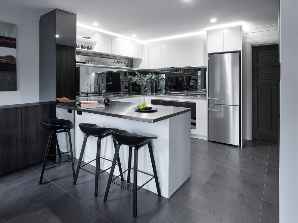Eat-in kitchen - large modern u-shaped ceramic tile eat-in kitchen idea in Other with an integrated sink, white cabinets, stainless steel countertops, glass sheet backsplash, stainless steel appliances and a peninsula