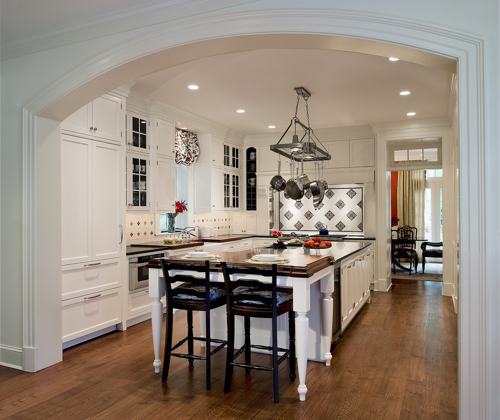 Inspiration for a large timeless l-shaped dark wood floor and brown floor enclosed kitchen remodel in DC Metro with shaker cabinets, white cabinets, an island, a farmhouse sink, granite countertops, white backsplash, ceramic backsplash and paneled appliances