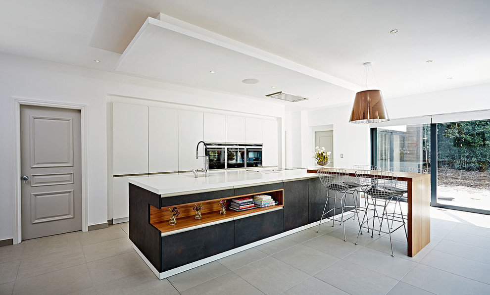 This is an example of a l-shaped kitchen in Cheshire with flat-panel cabinets, white cabinets and an island.