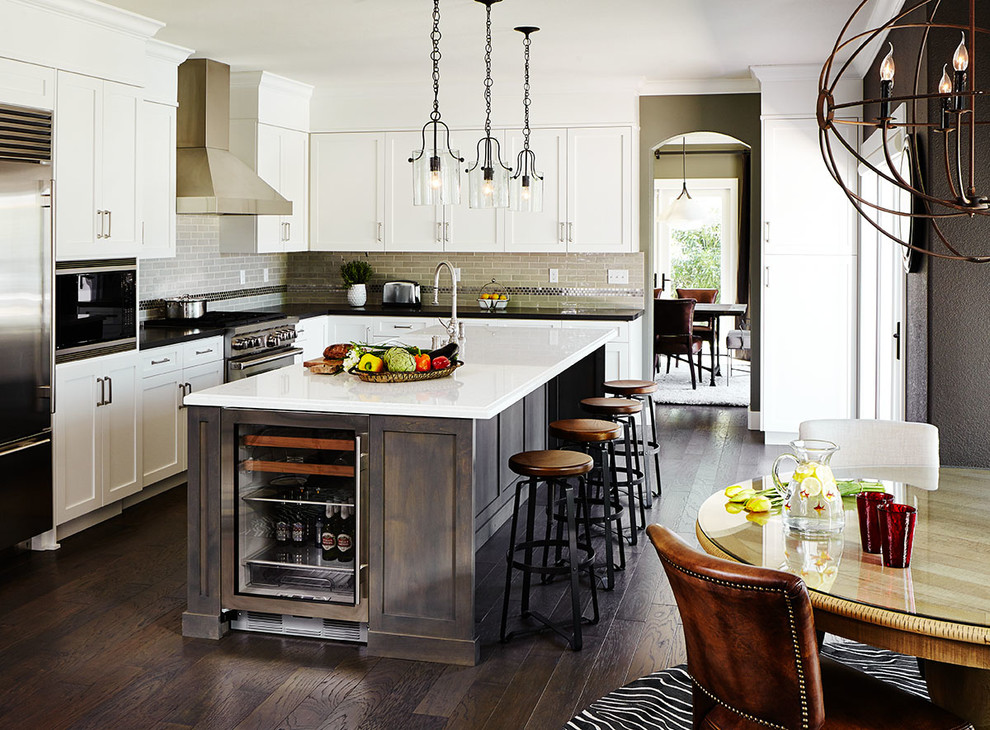 Example of a large transitional l-shaped dark wood floor open concept kitchen design in San Francisco with a farmhouse sink, shaker cabinets, quartz countertops, beige backsplash, subway tile backsplash, stainless steel appliances and an island