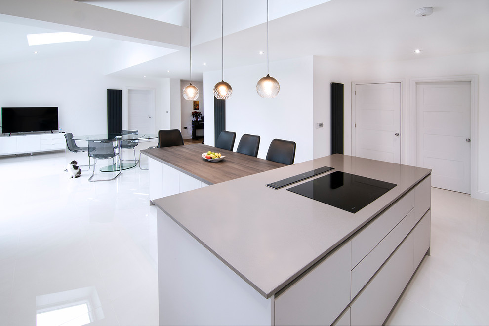 Large contemporary l-shaped kitchen/diner in London with an integrated sink, flat-panel cabinets, grey cabinets, engineered stone countertops and an island.