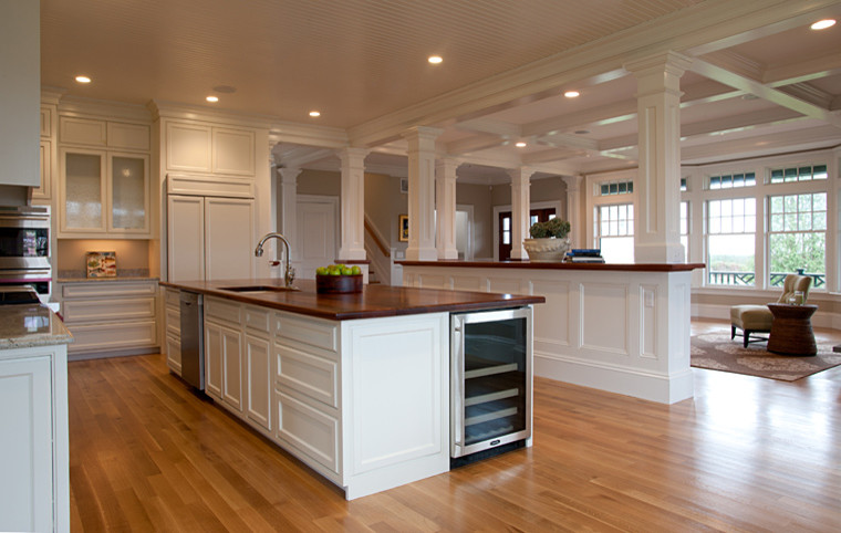 Huge elegant l-shaped medium tone wood floor open concept kitchen photo in Boston with two islands, recessed-panel cabinets, white cabinets, wood countertops, stainless steel appliances and a drop-in sink