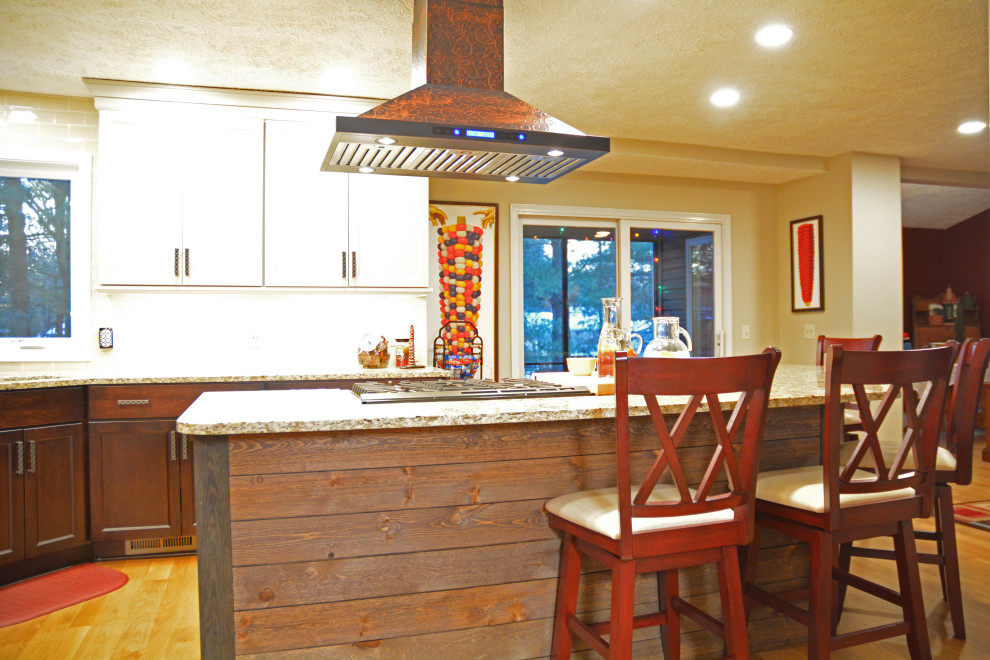 Inredning av ett eklektiskt stort flerfärgad flerfärgat kök, med en undermonterad diskho, släta luckor, vita skåp, granitbänkskiva, gult stänkskydd, stänkskydd i keramik, rostfria vitvaror, mellanmörkt trägolv, en köksö och brunt golv