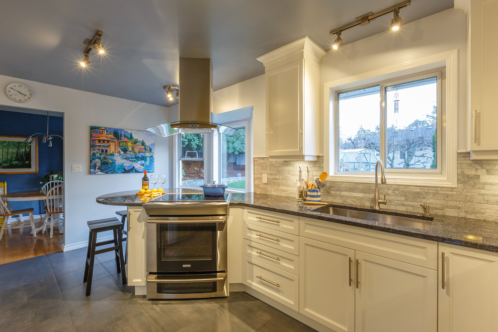 Modern inredning av ett avskilt, stort u-kök, med en undermonterad diskho, skåp i shakerstil, vita skåp, granitbänkskiva, grått stänkskydd, stänkskydd i stenkakel, rostfria vitvaror, ljust trägolv och en halv köksö