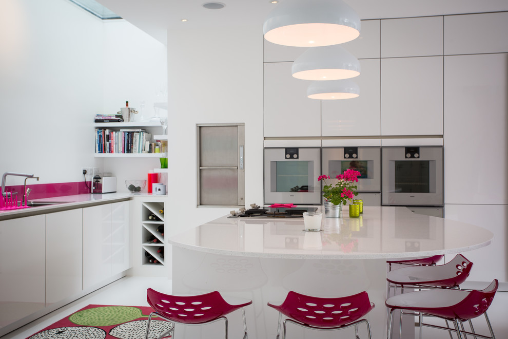 Immagine di una grande cucina design con ante lisce, ante bianche, top in superficie solida, paraspruzzi bianco, paraspruzzi con lastra di vetro e elettrodomestici in acciaio inossidabile