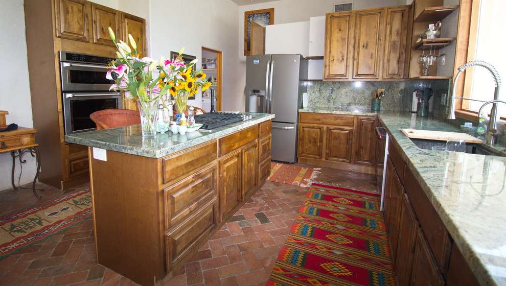Idéer för att renovera ett stort medelhavsstil grön grönt kök, med en undermonterad diskho, luckor med upphöjd panel, skåp i slitet trä, granitbänkskiva, grönt stänkskydd, stänkskydd i sten, rostfria vitvaror, tegelgolv, en köksö och rött golv